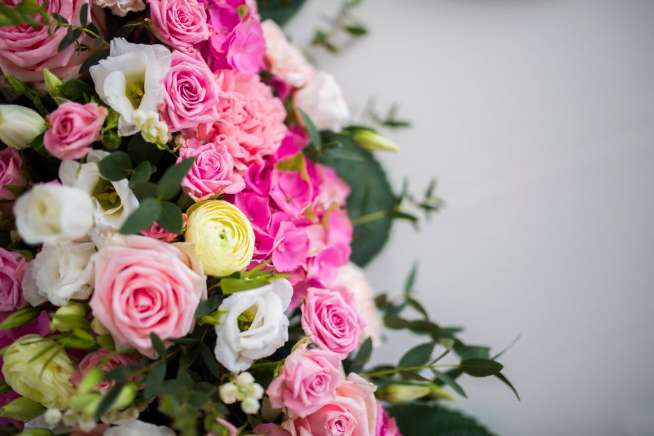 A floral arrangement featuring a variety of fresh flowers including pink roses, white lisianthus, and pink carnations, accented with green foliage. The bouquet is densely packed with blooms, showcasin